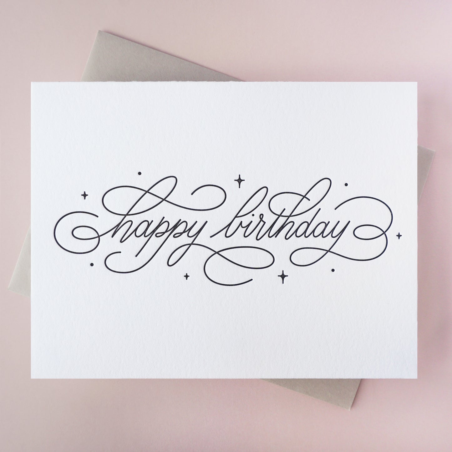 Carte letterpress avec le message calligraphié "Happy birthday" imprimé en noir et son enveloppe grise assortie 